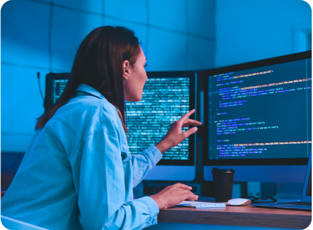 Female developer coding on multiple screens.